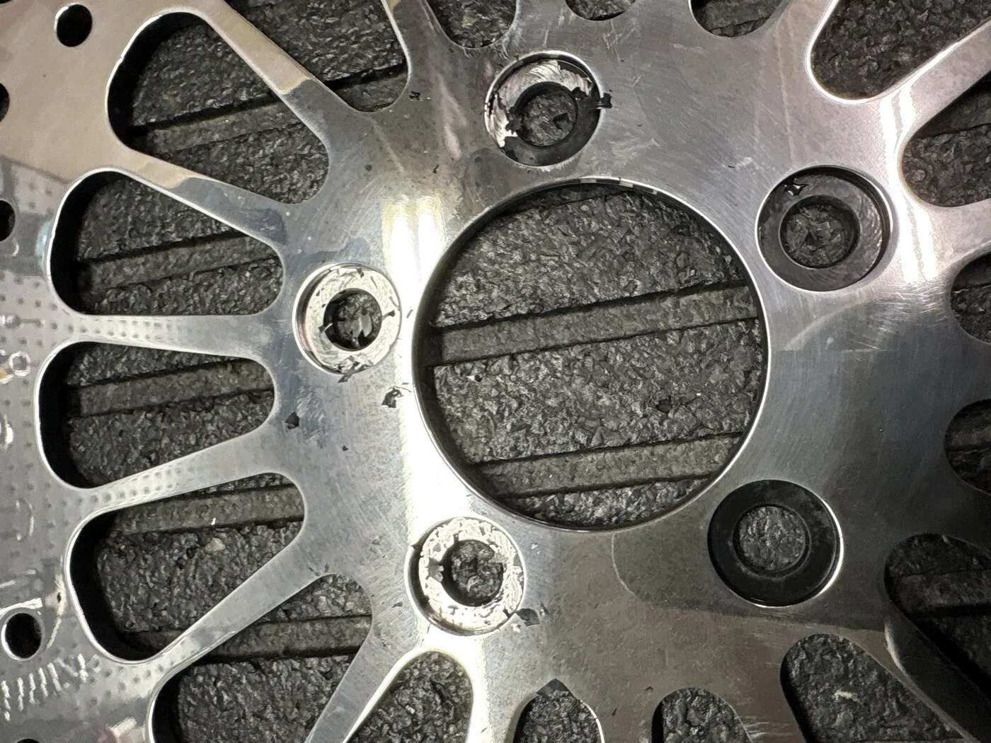Mill scale at the rotor bolt seats. Scraping has started on the seats; the dark seats still carry scale, which would crush under the bolt heads and let clamping force fall away.