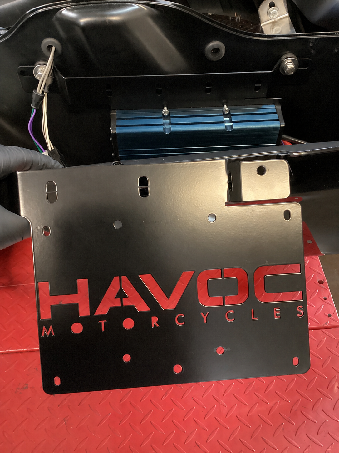 Road-Lock saddlebag amplifier bracket installed inside a Harley-Davidson saddlebag, with the blue amplifier mounted on the factory mounting points above it
